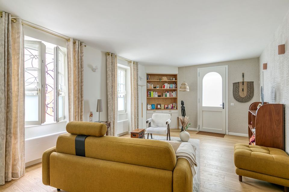 Le cabinet d’Emmanuelle Galy : le canapé moutarde, le fauteuil blanc, la bibliothèque en chêne et la porte d’entrée